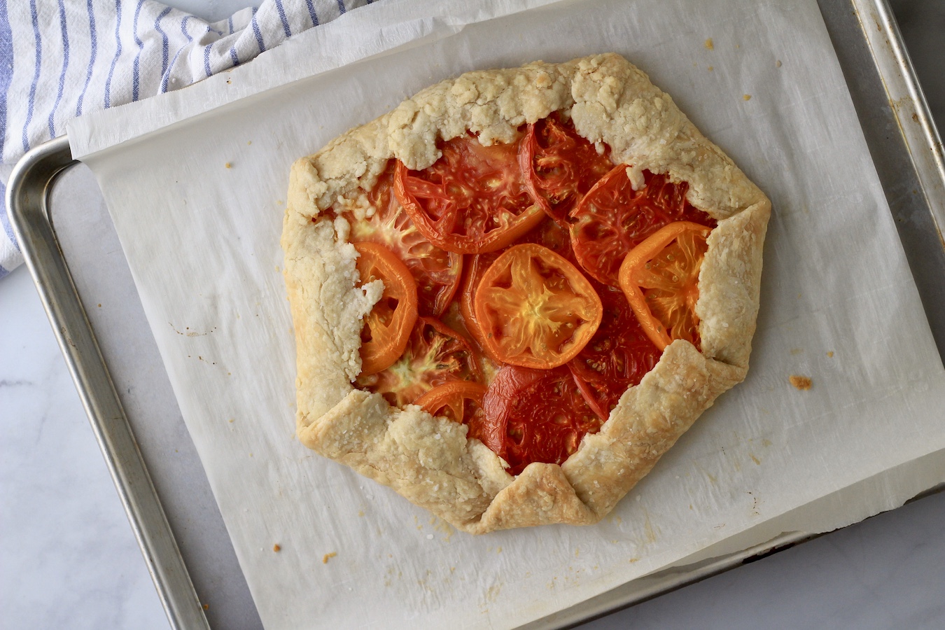 Baked tomato galette on a parchment paper on a baking sheet.