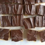 Cut squares of chocolate peanut butter rice krispies on a marble counter.