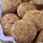 A woven basket with parchment paper filled with pumpkin spice snickerdoodles.