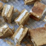 Many snickerdoodle ice cream sandwiches on a parchment paper.
