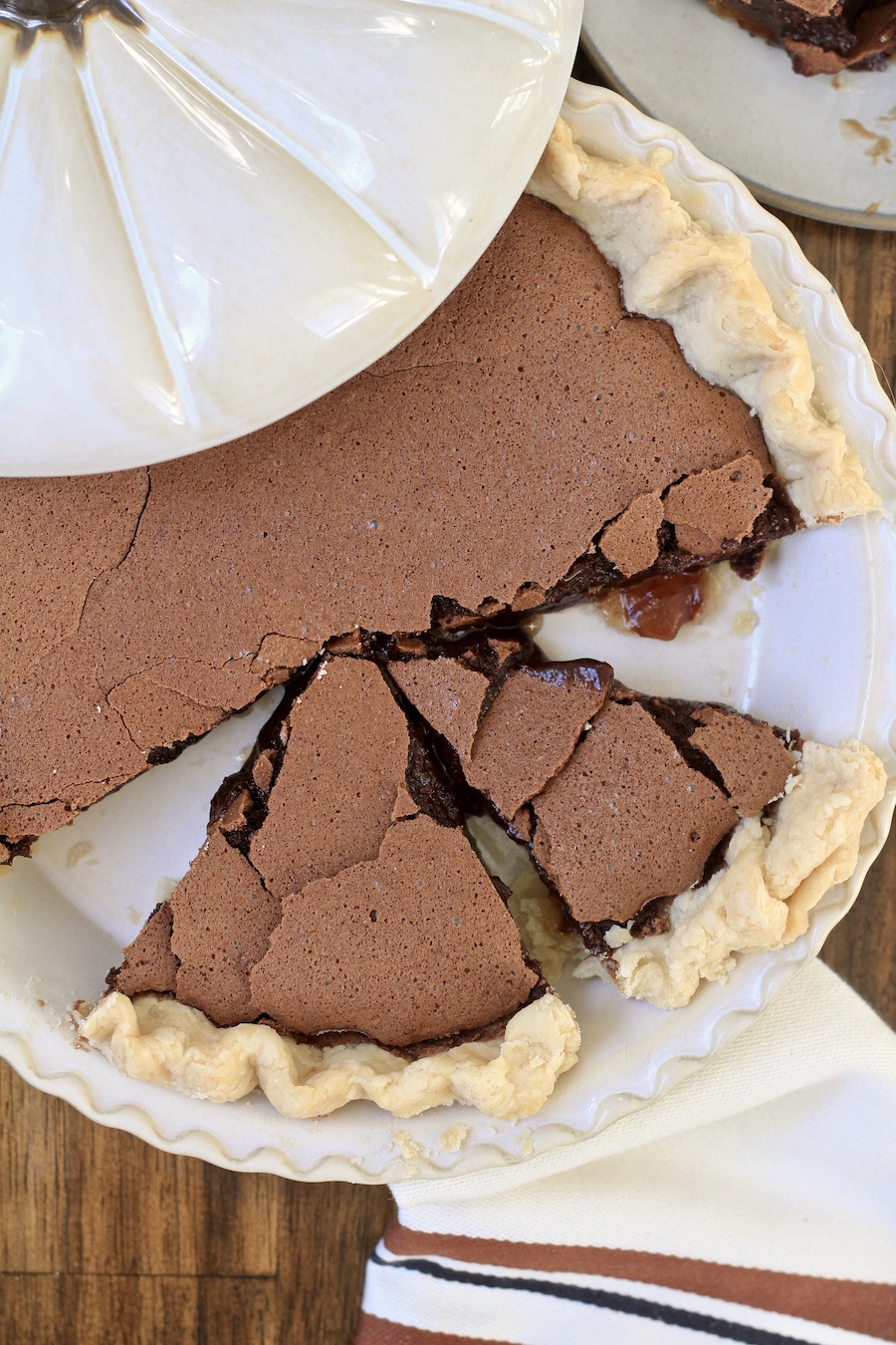 Two cut slices of chocolate chess pie in a pie pan with a pumpkin shaped lid.