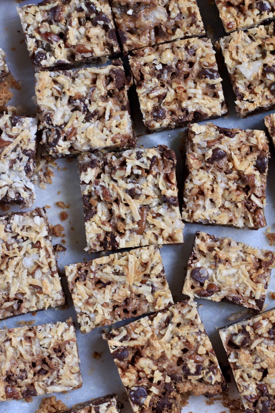 Square cut magic cookie bars on parchment paper.
