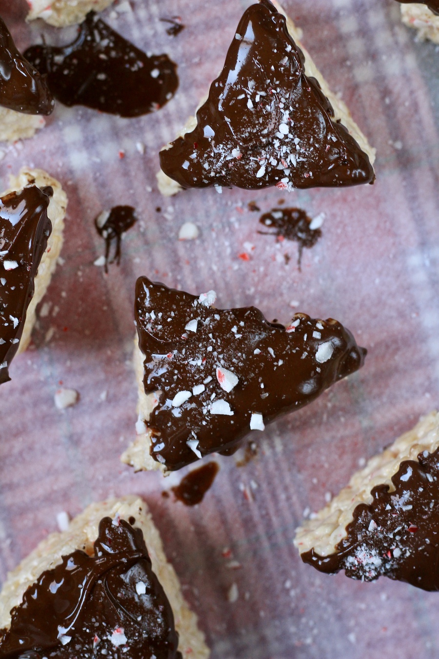 Chocolate dipped and peppermint sprinkled rice krispie treats on a parchment paper.