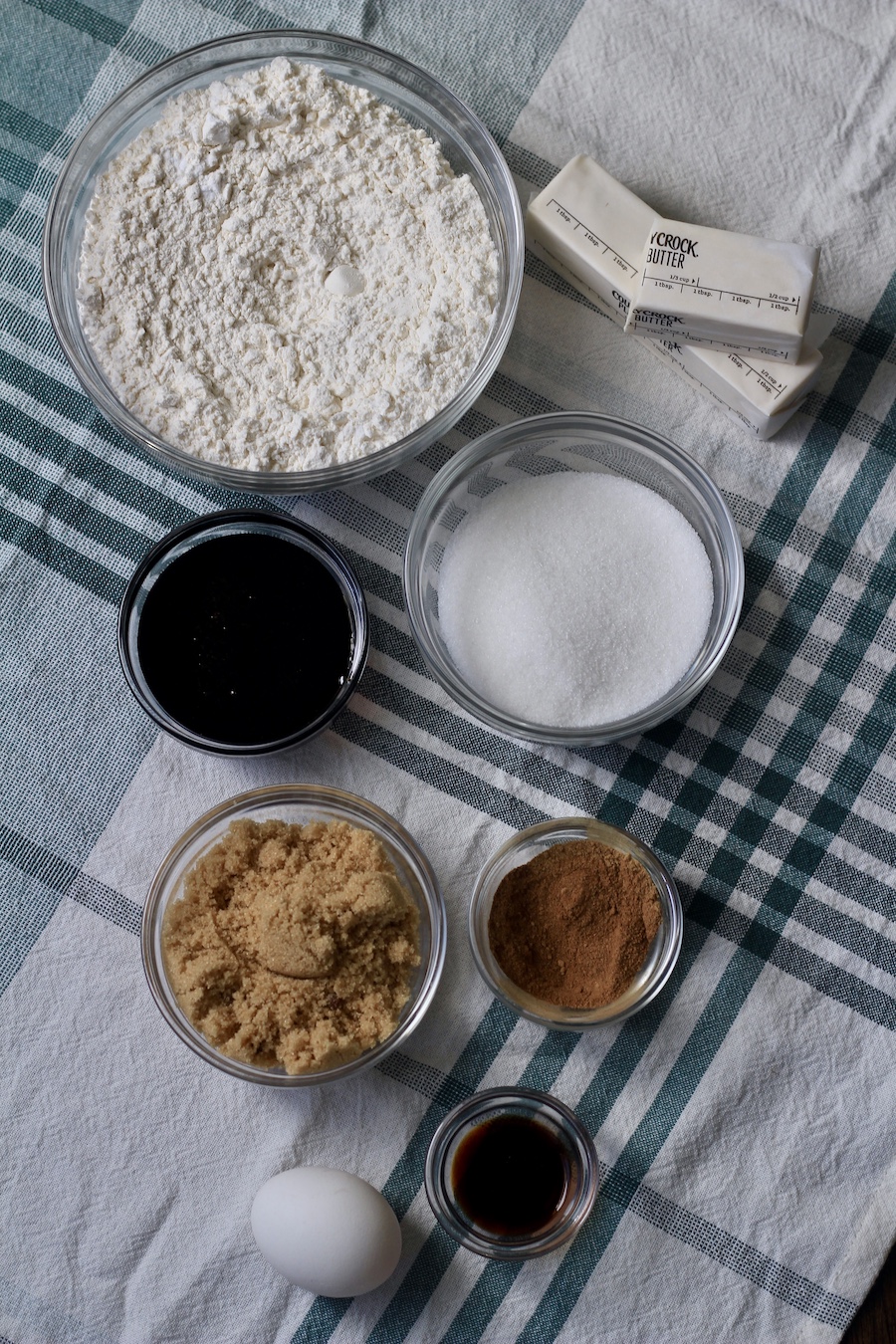 Ingredients for soft ginger cookies in glass bowls on a white and green towel.