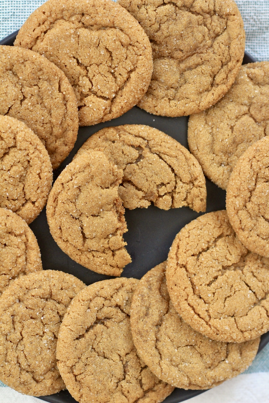 A blue plate of soft ginger cookies with a cookie in the middle broken in half.