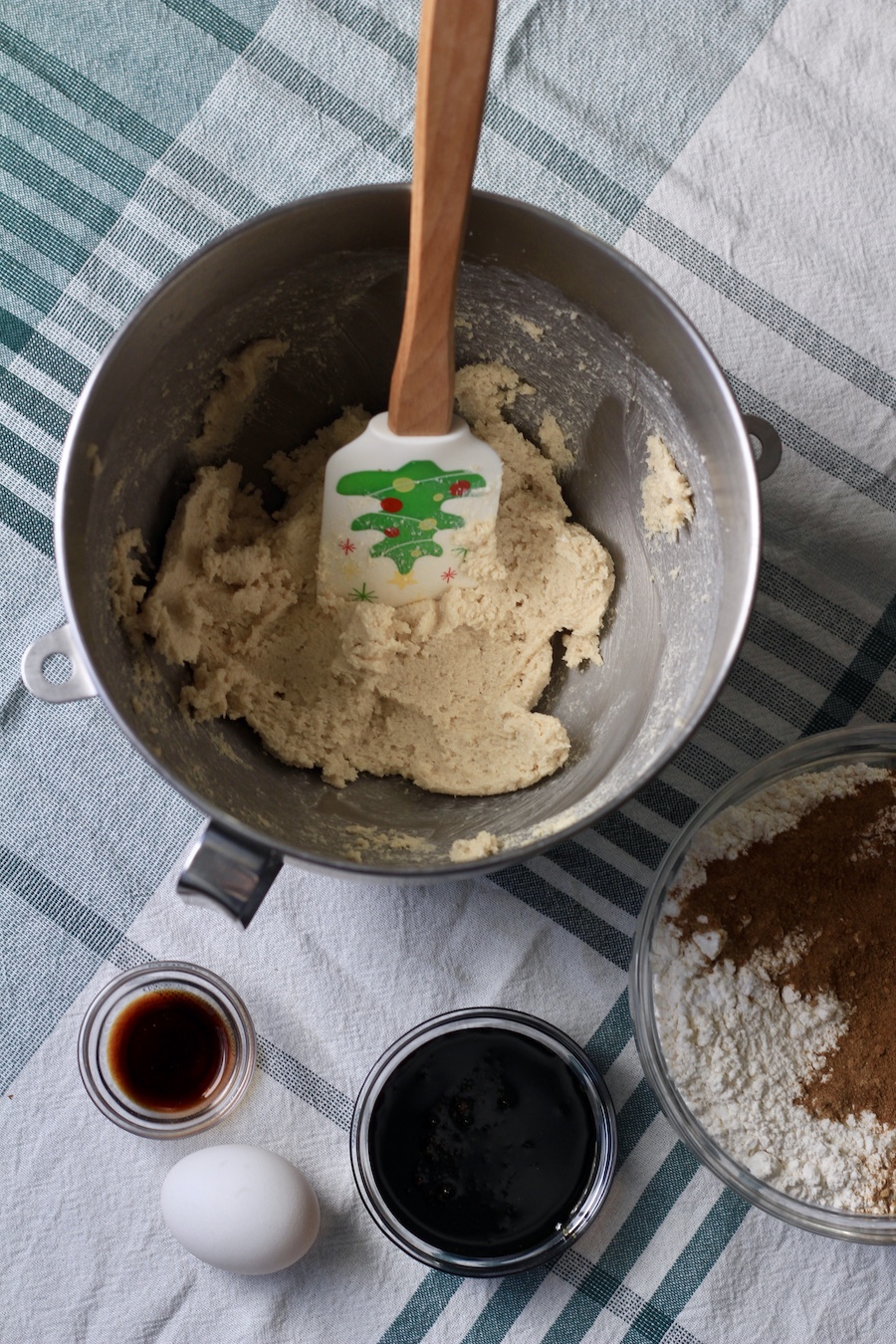 A mixing bowl with creamed butter and sugar, with a bowl of vanilla, molasses, and the flour mixture below.