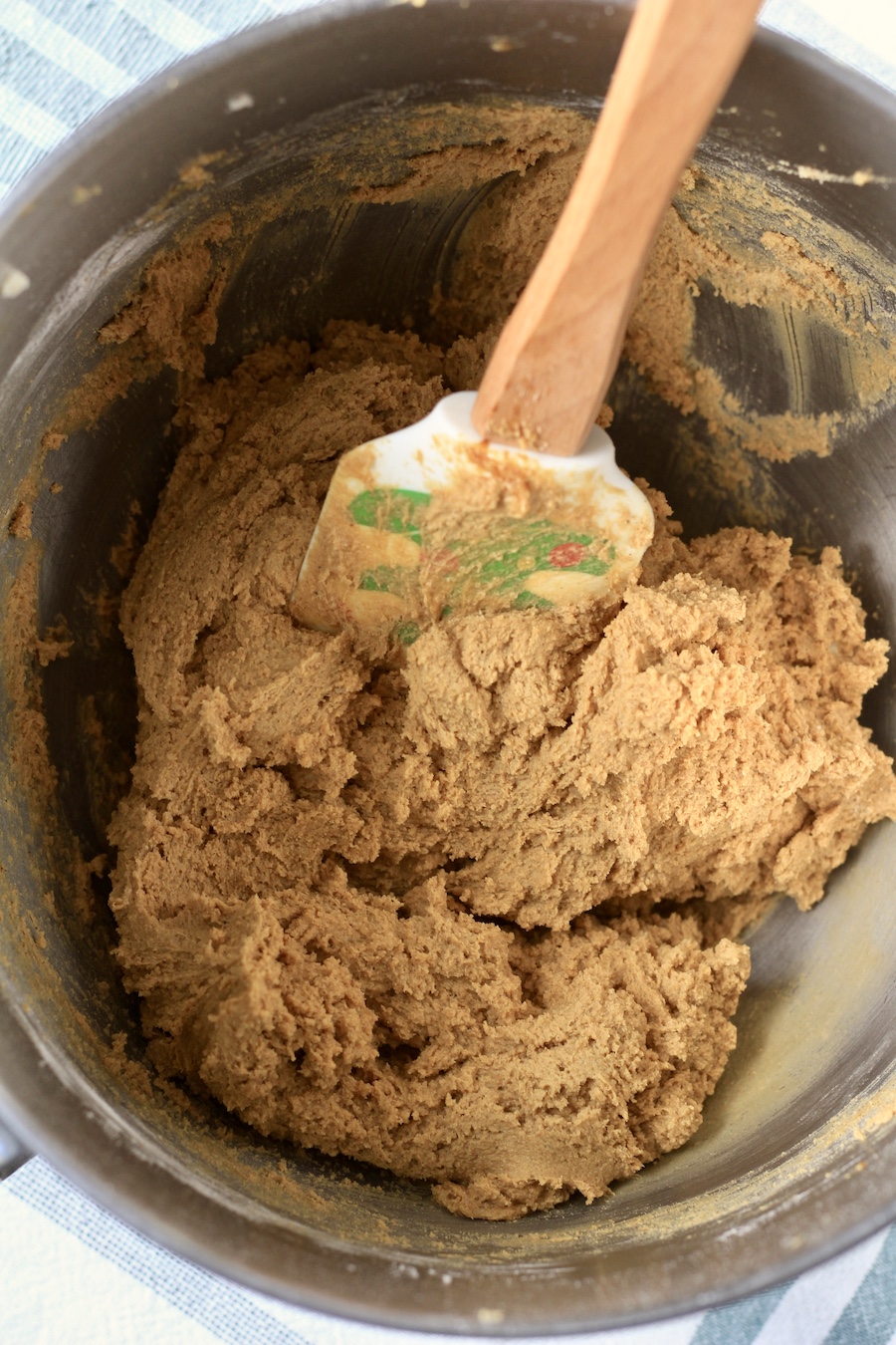 A mixing bowl with soft ginger cookie dough with a spatula.