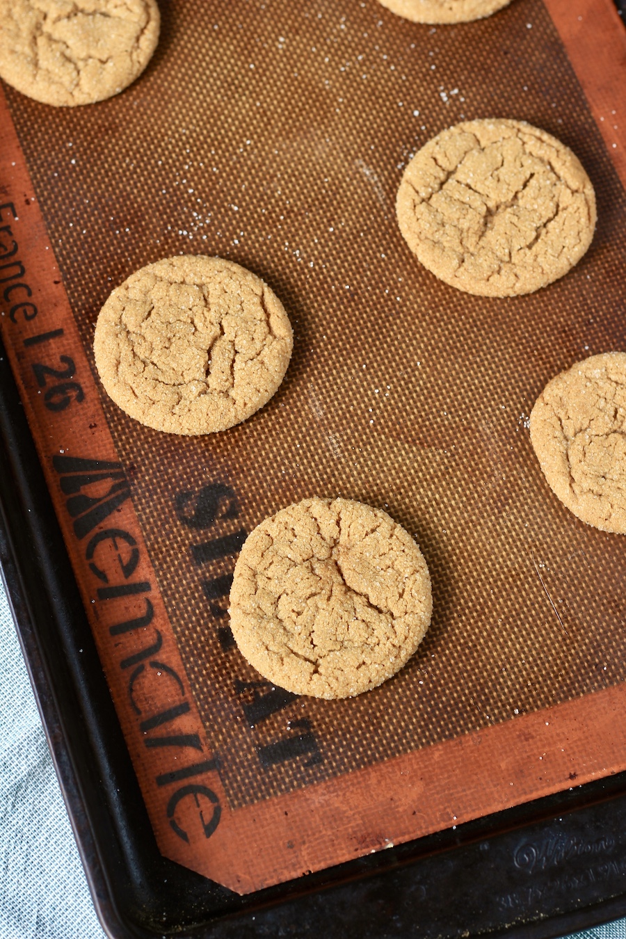 Baked soft ginger cookies on a lined baking sheet.