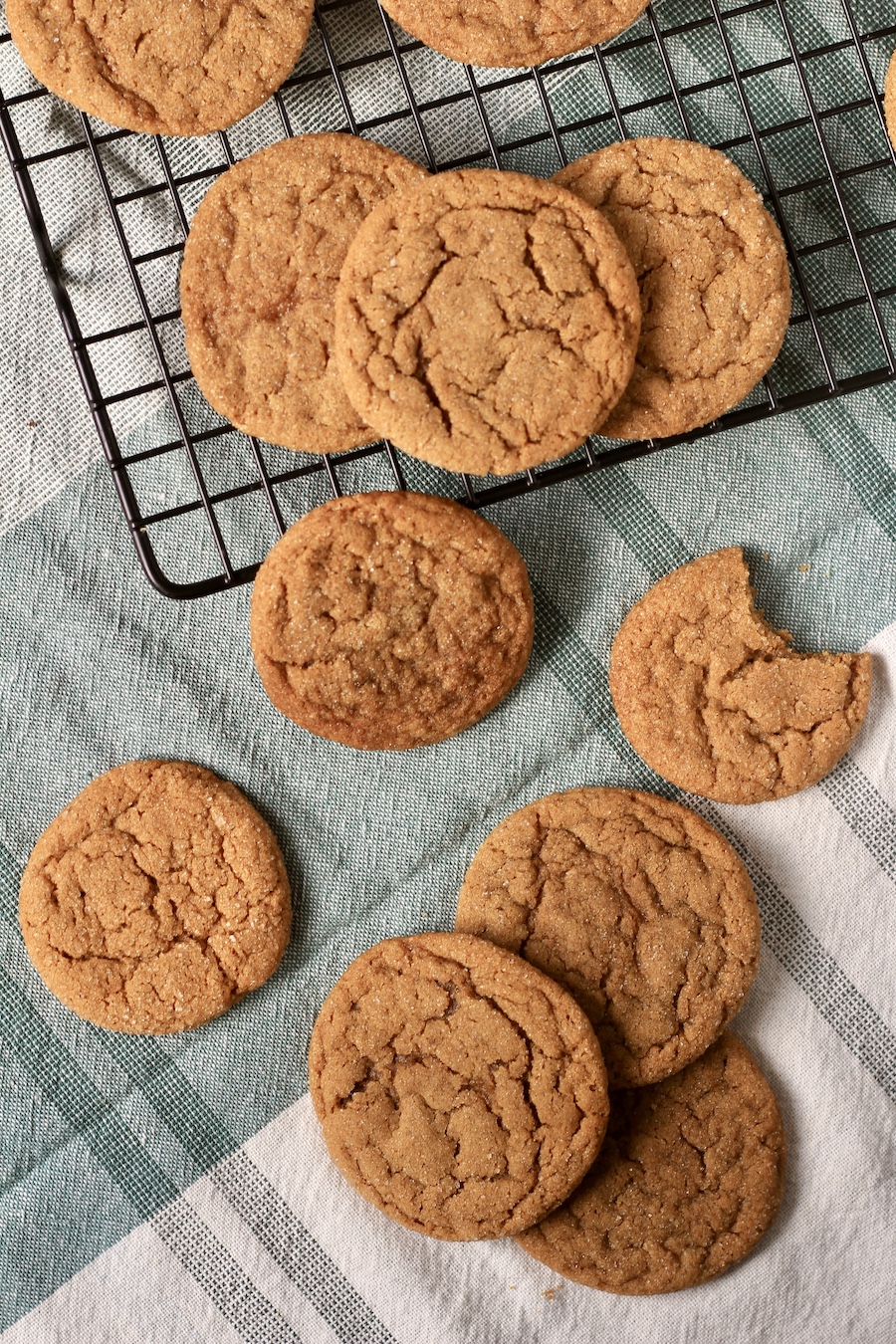 Soft ginger cookies on a cooling rack with some cookies on a towel in front.