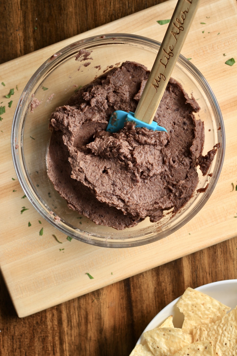 The creamy bean dip in a glass bowl with a rubber spatula.