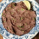A blue bowl of black bean dip on a white towel.
