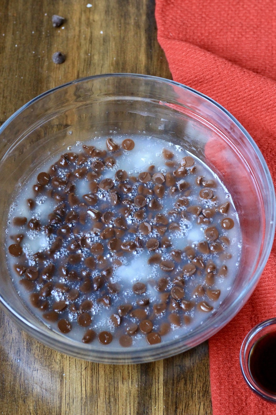 Chocolate chips and sweetened condensed coconut milk before melting in a glass bowl.