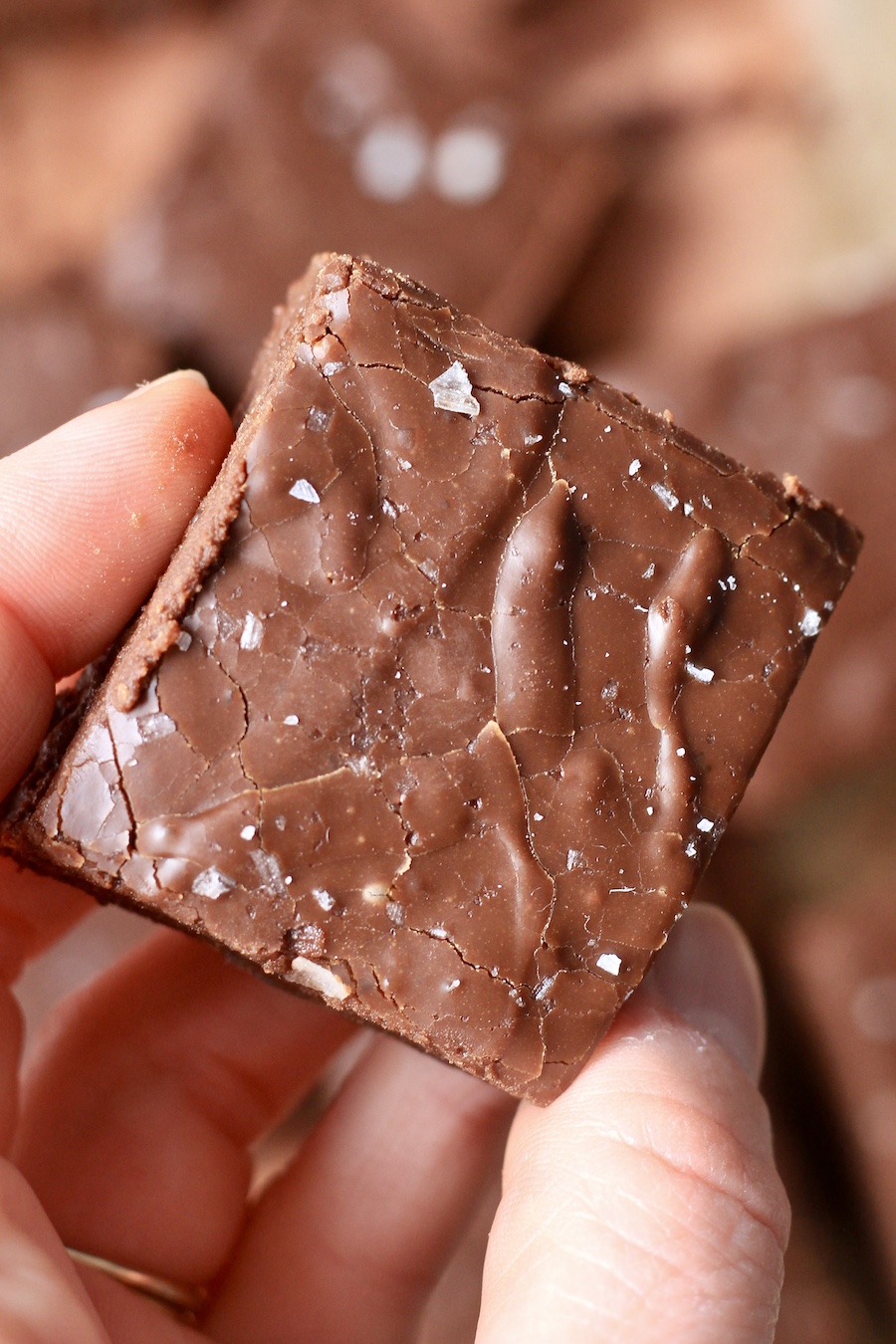 A hand holding a square of easy chocolate fudge.