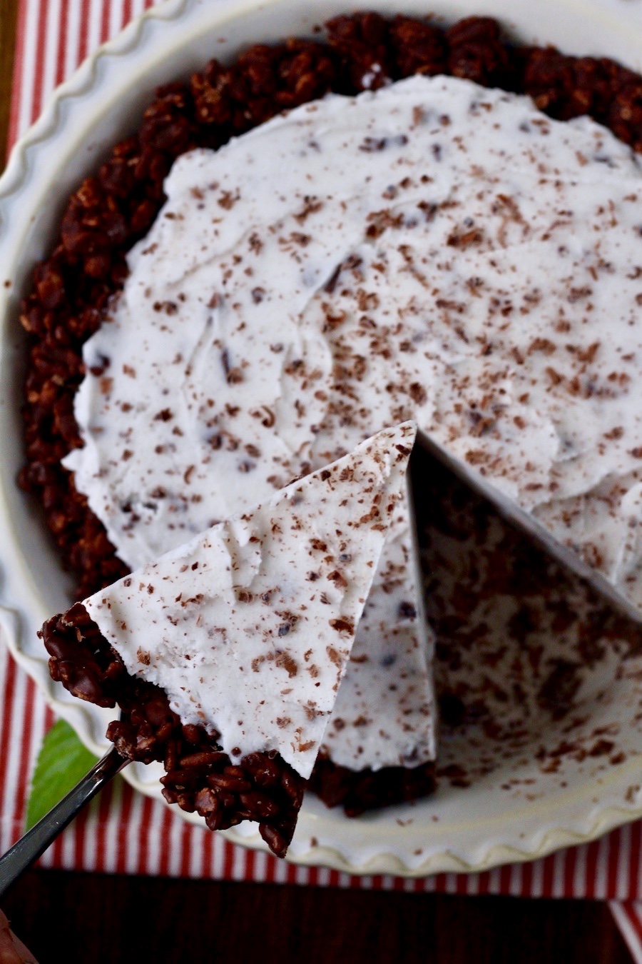 A Mint Ice Cream Pie with a slice out of the pie plate being held above.