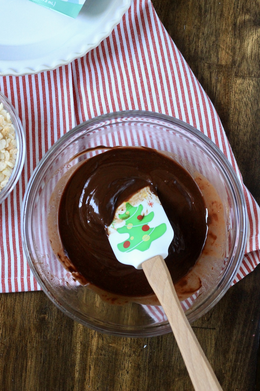 Melted dairy-free chocolate with a spatula on a white and red striped dish towel.