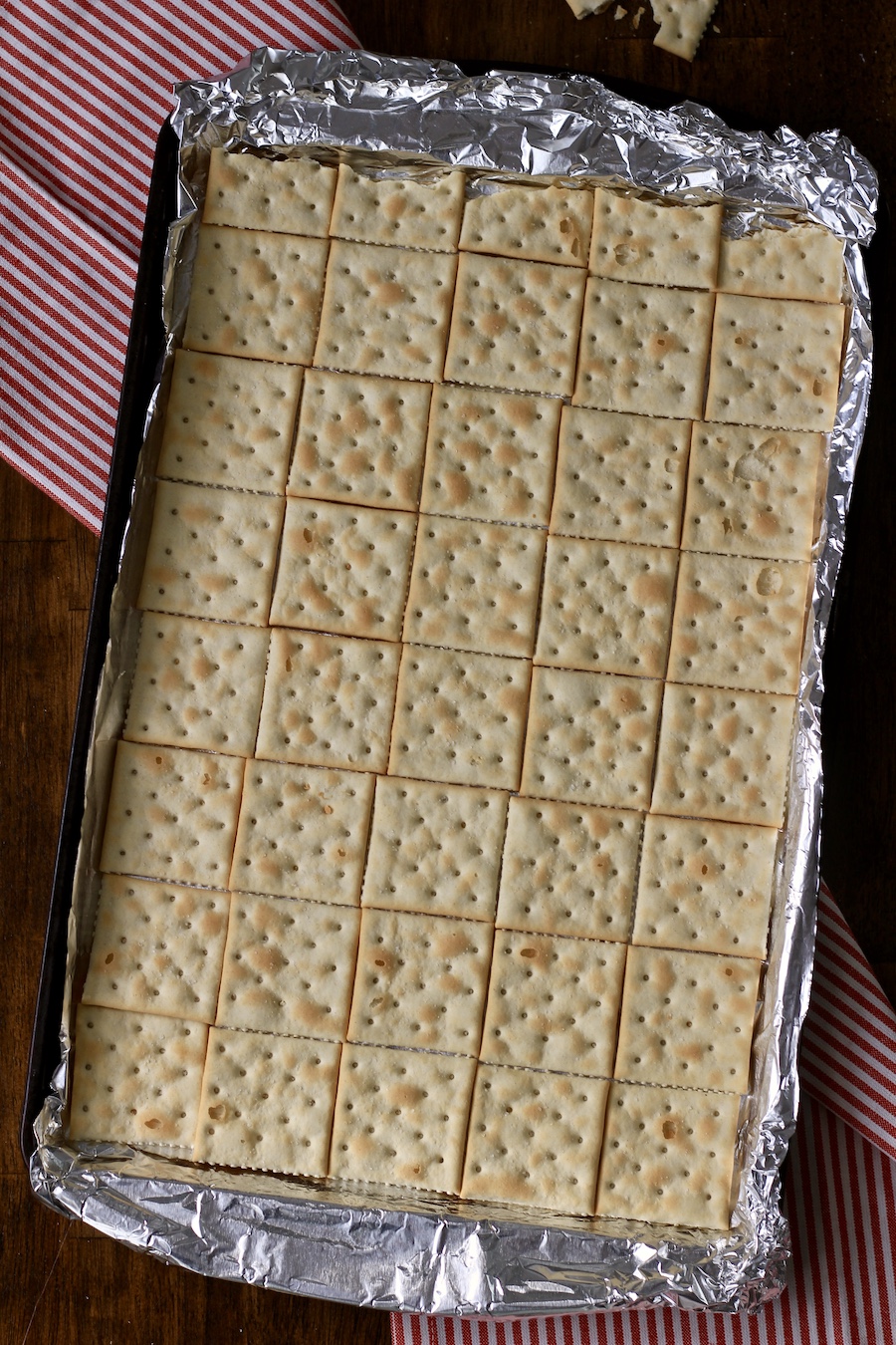 A baking sheet lined with foil and layered with saltine crackers.