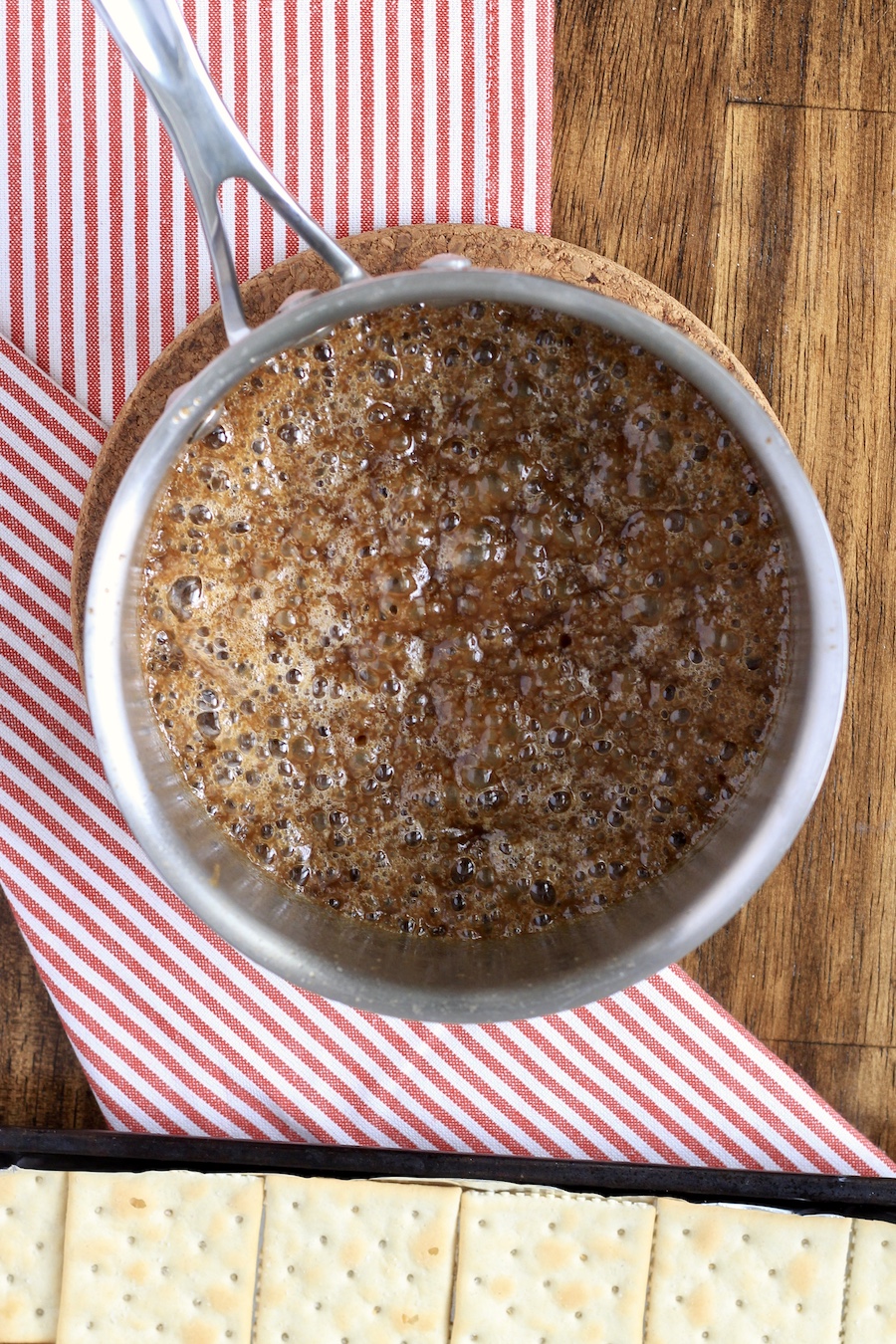 A sauce pan with toffee melted in a red and white dish towel.
