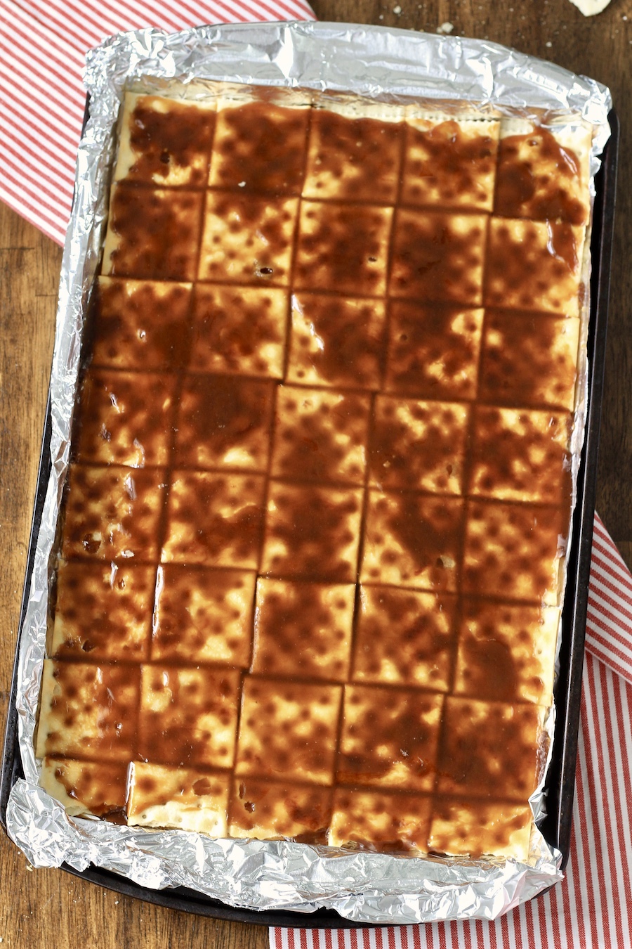 A baking sheet lined with foil topped with saltines covered with toffee.