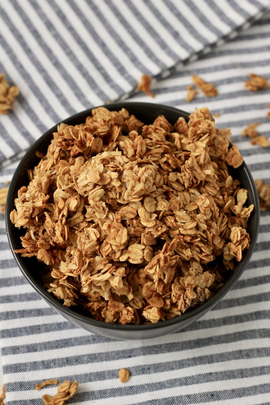 A blue bowl with crunch coconut granola on a blue and white striped dish towel.