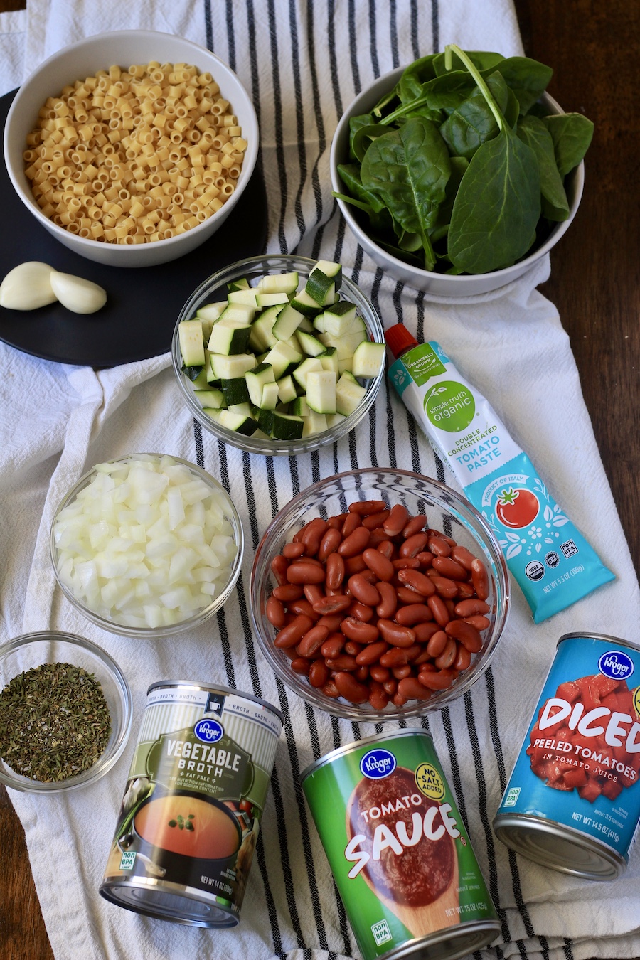 Ingredients for minestrone soup on a white and blue dish towel.