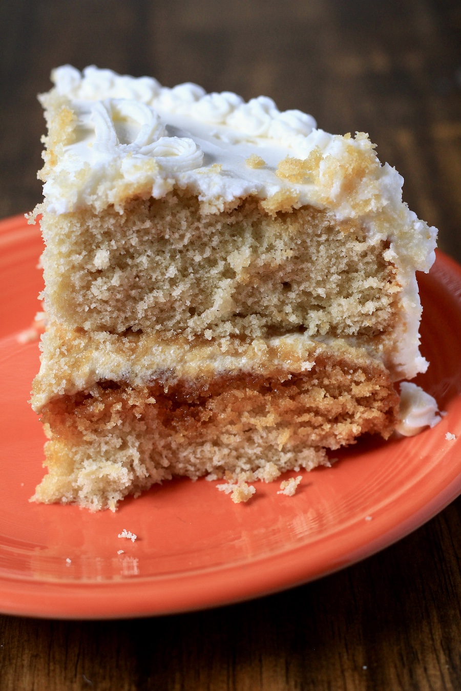 A slice of salted caramel cake on an orange plate.