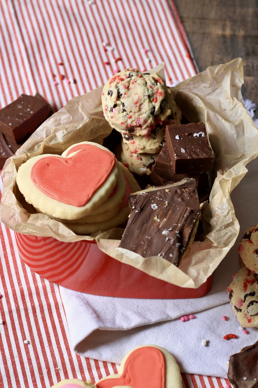 Valentine's Day dessert box filled with cookies in a red tin on a white towel.