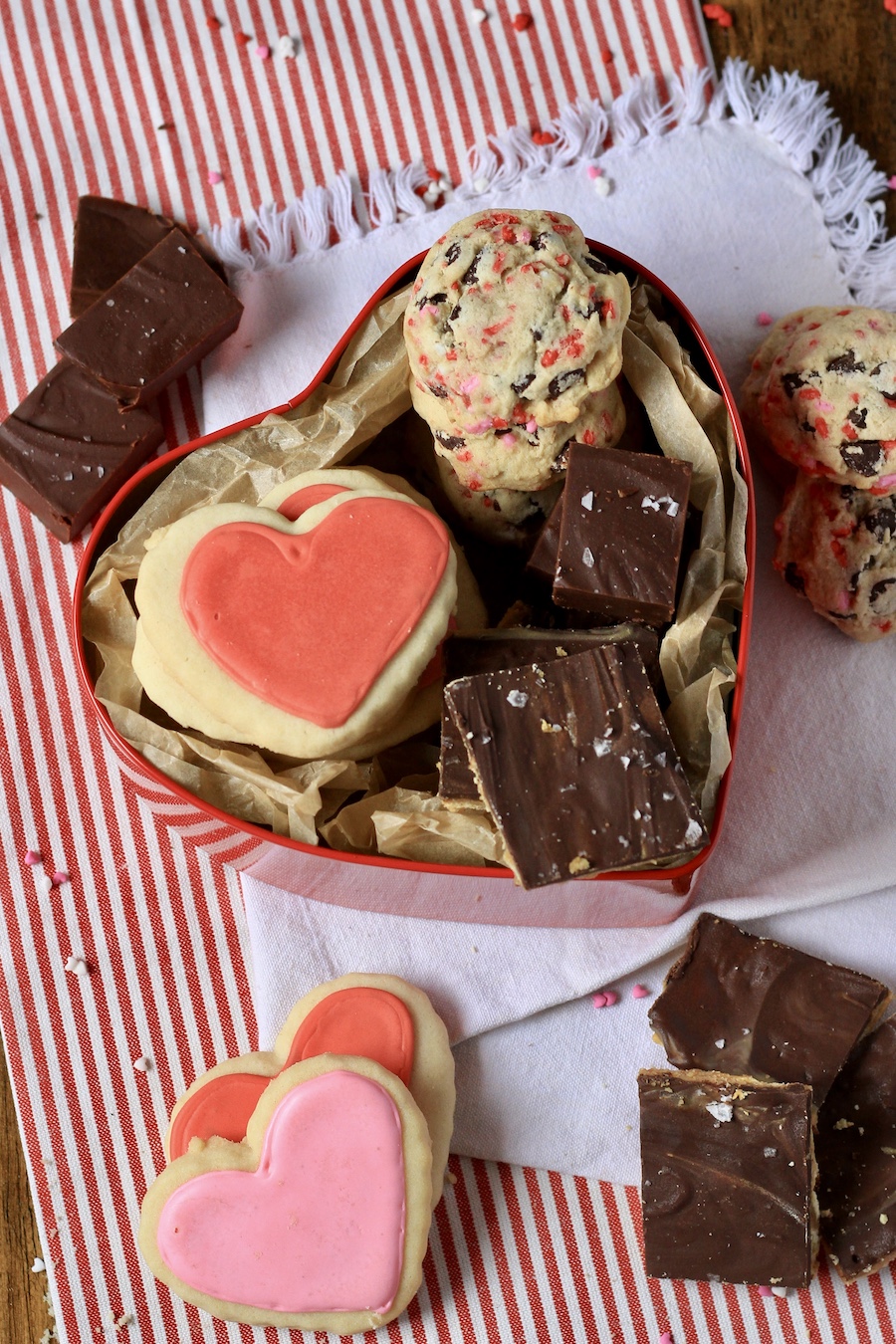 A valentine's day dessert box in a heart shape in the middle with extra cookies and fudge around the outside.