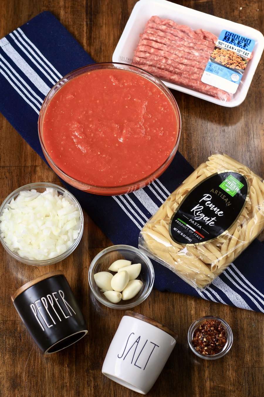 Ingredients for Arrabbiata meat sauce on a wooden counter.