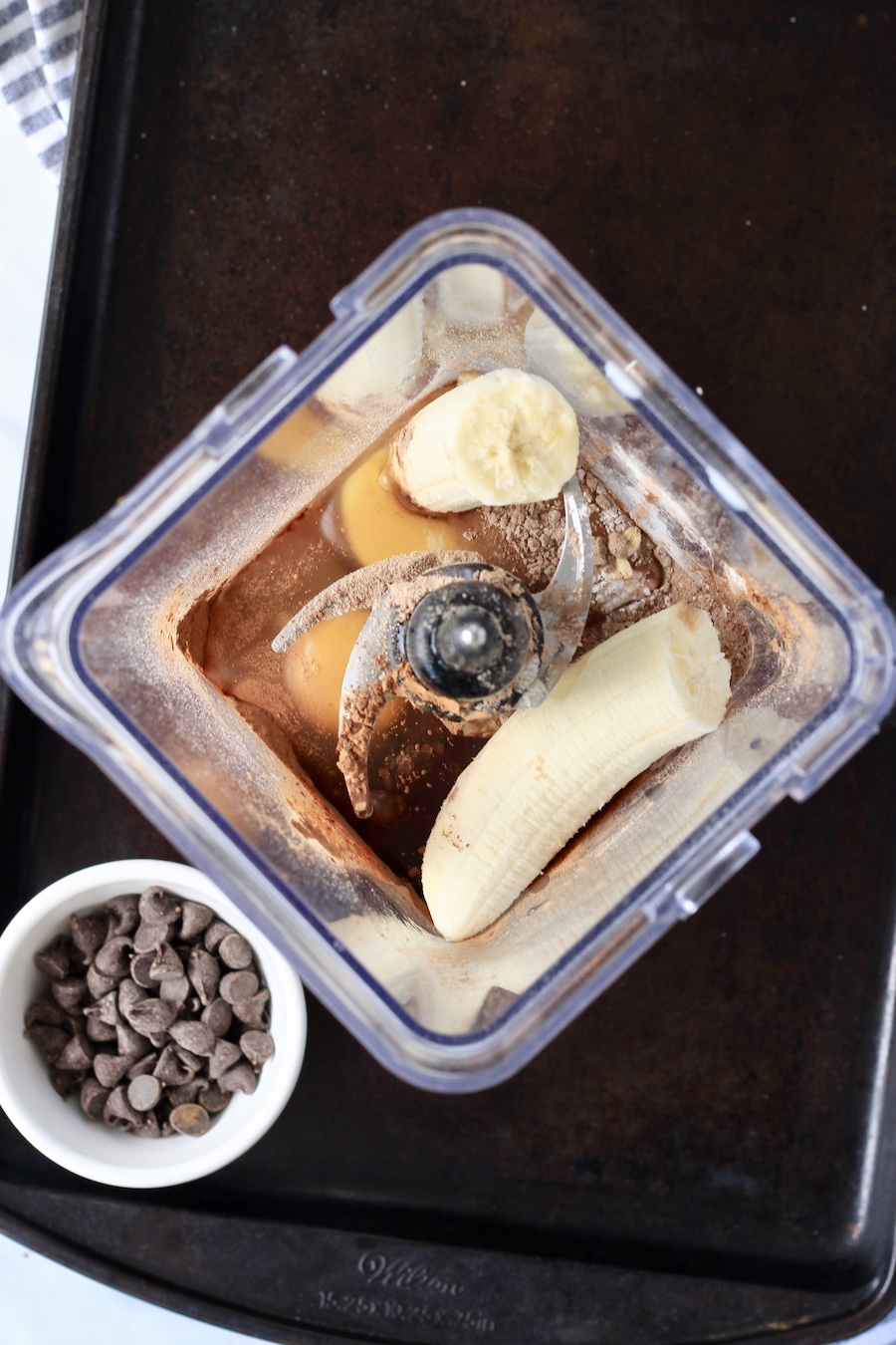 A blender with the ingredients for chocolate baked oat on a baking sheet.