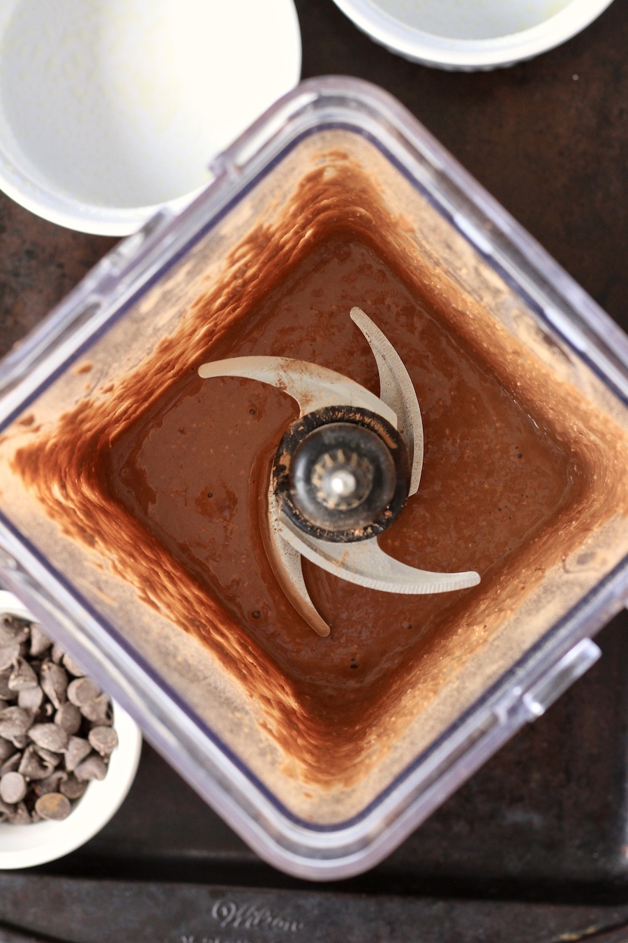 A blender on a baking sheet with the chocolate baked oats after blending.