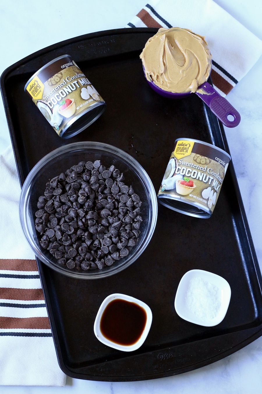 A rimmed baking sheet with ingredients for chocolate peanut butter fudge.