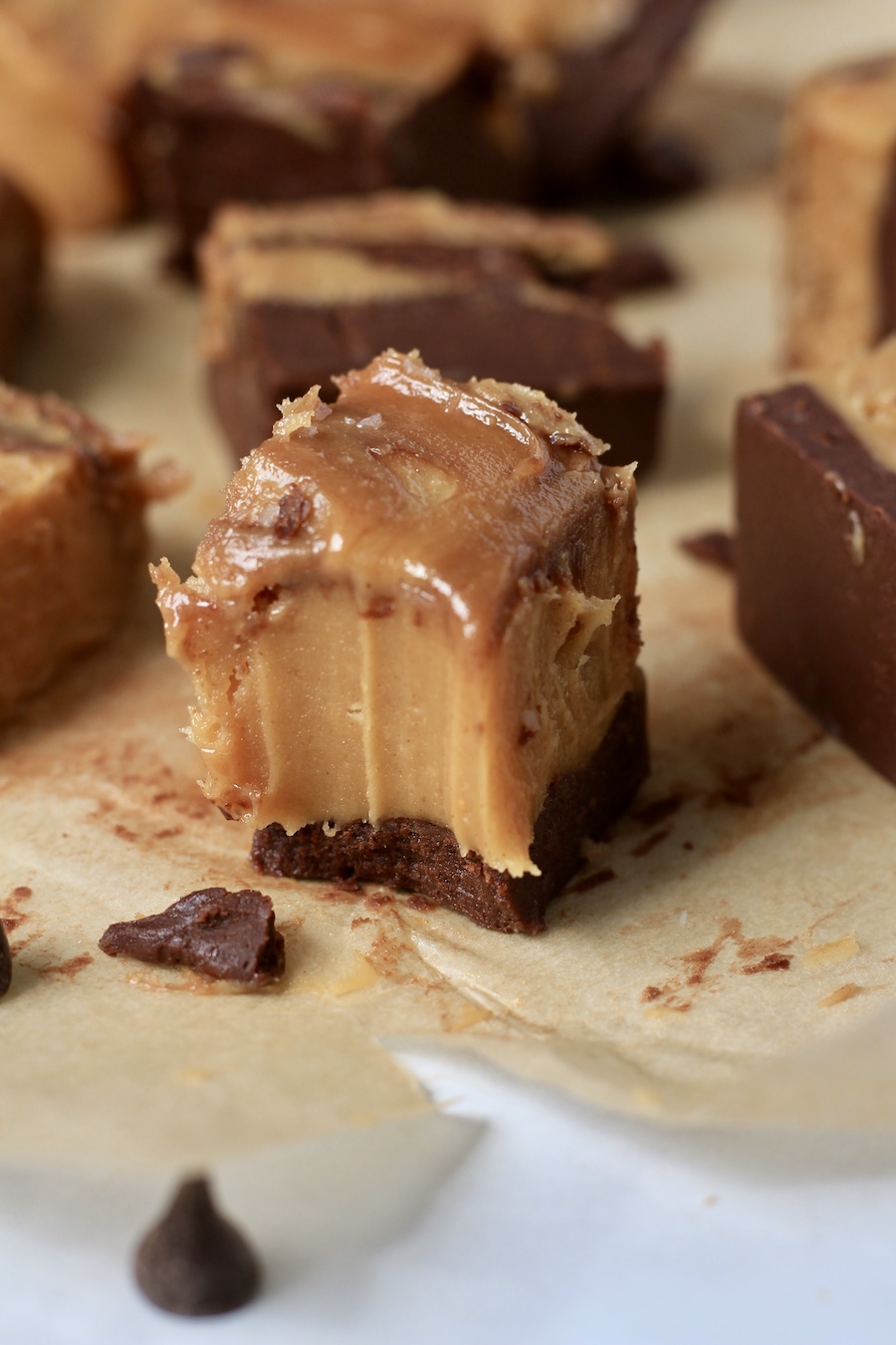 A piece of parchment paper with chocolate peanut butter fudge with a bite taken out.