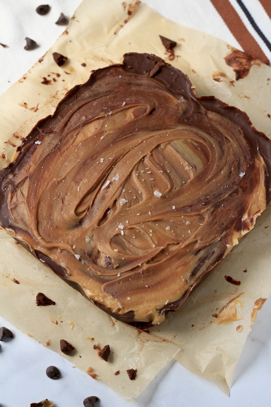 A slab of fudge on a piece of parchment paper with chocolate chips around.