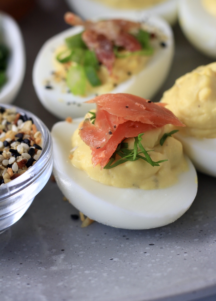 A close up shot of a smoked salmon topped deviled egg on a blue-grey platter.