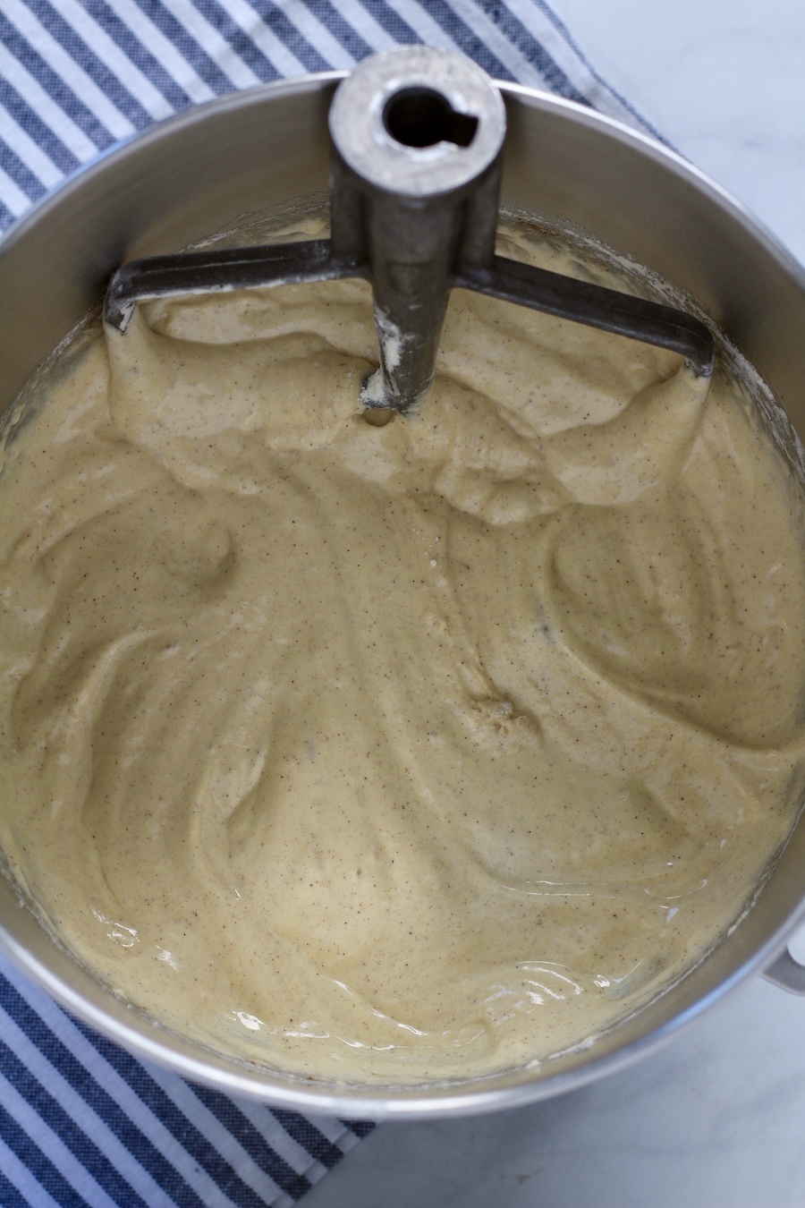 Top down silver bowl with cake batter and a paddle.