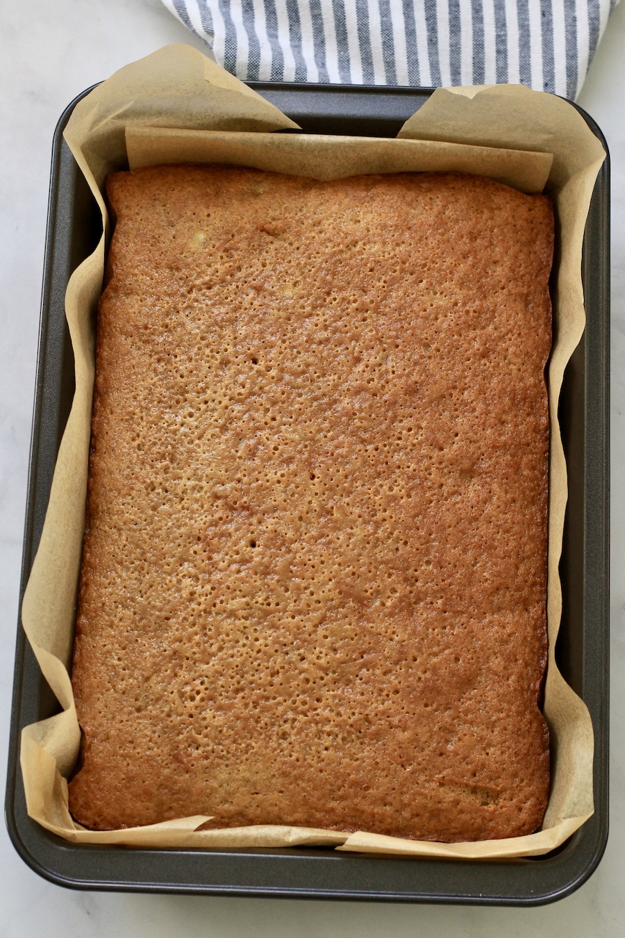 Banana snack cake after baking in a pan with parchment paper.