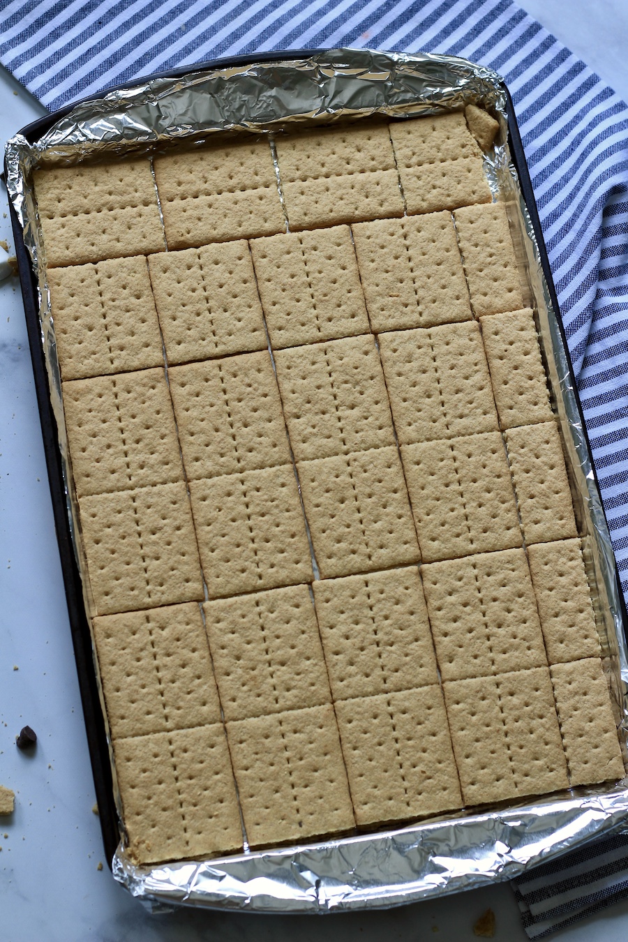 A rimmed baking sheet lined with aluminum foil and a layer of graham crackers.