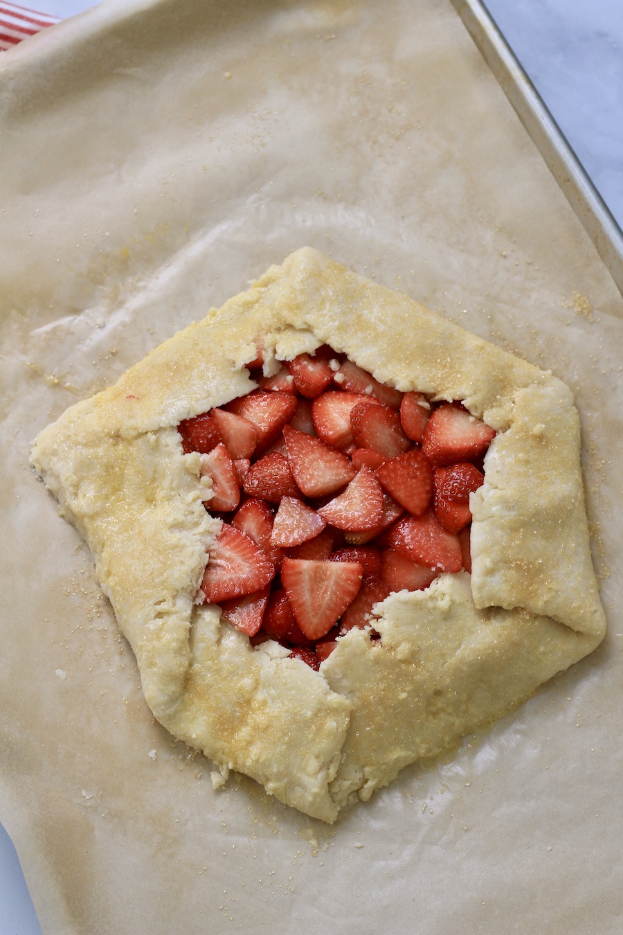 An unbaked strawberry lemon galette topped with sugar in the raw.