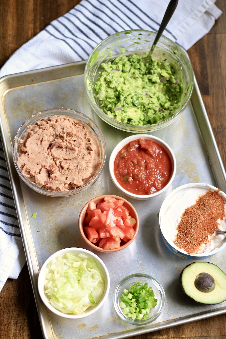 Ingredients for 7 layer dip in bowls on a baking sheet.