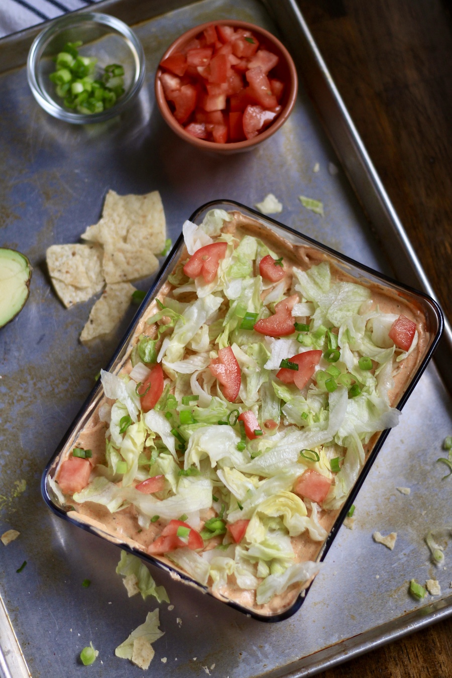 The 7 layer dip in a glass dish topped with lettuce and diced tomato.