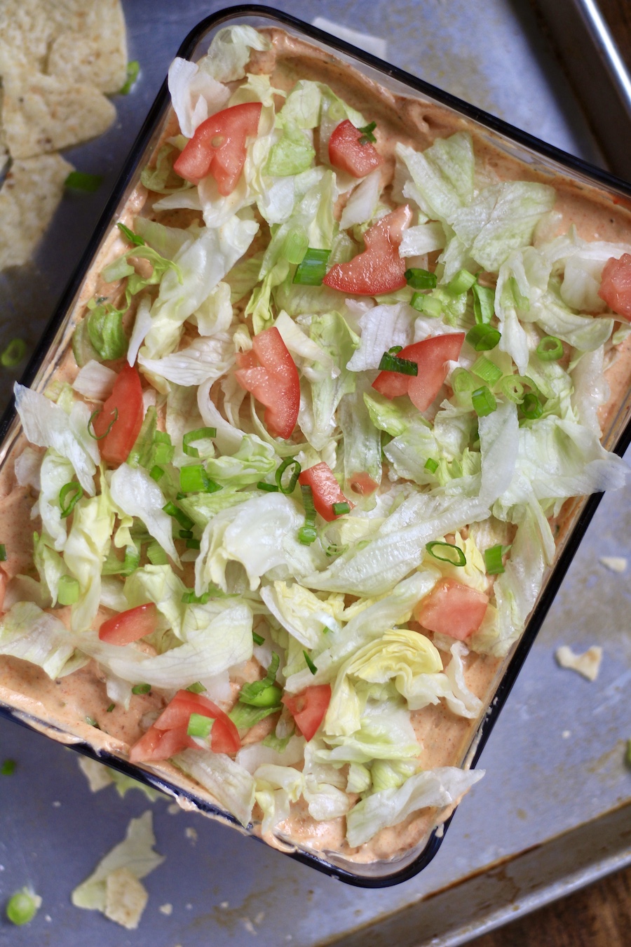 A top down photo of vegan 7 layer dip with shredded lettuce and diced tomato.