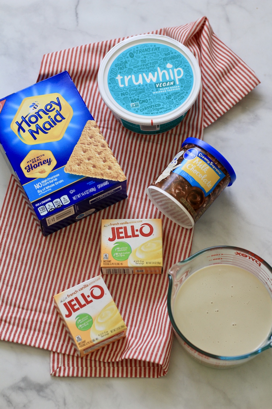 Ingredients for chocolate eclair dessert with a red and white striped towel.