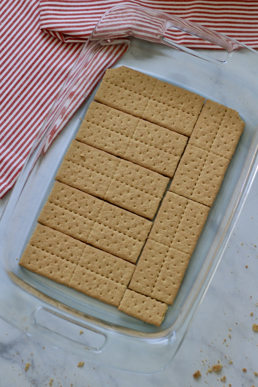 The first layer of graham crackers on the bottom of the baking dish.