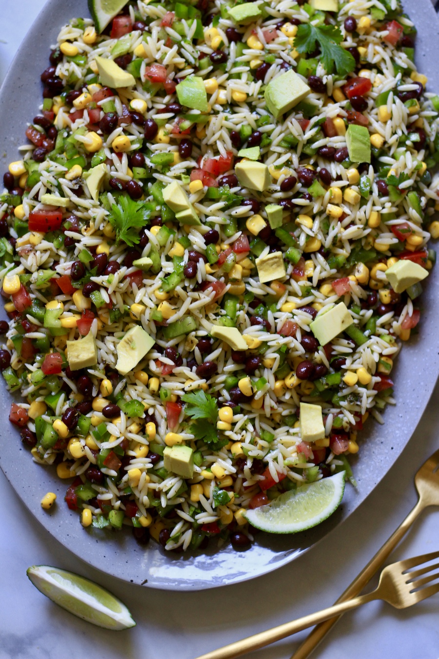 A top down photo of a blue platter with texas caviar pasta salad and a fork in the bottom right.