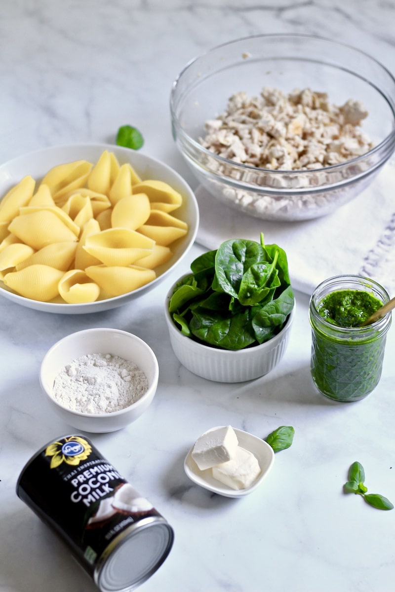 Ingredients for chicken pesto stuffed shells on a white counter.