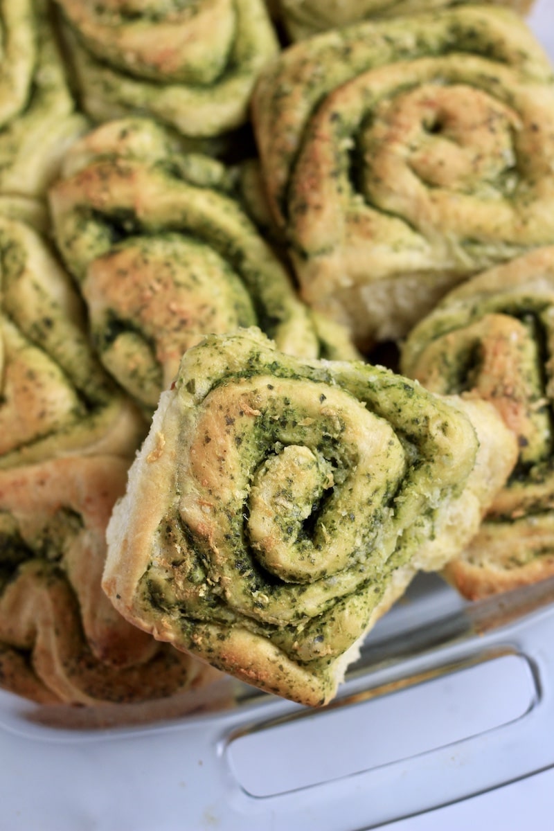 A pesto roll on top of a pan of other savory pesto rolls.