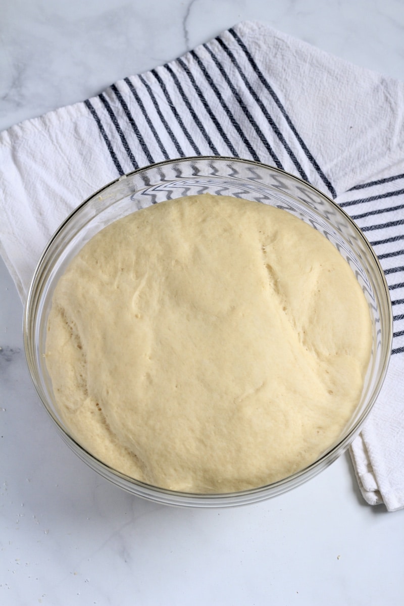 A glass bowl with bread dough after rising.
