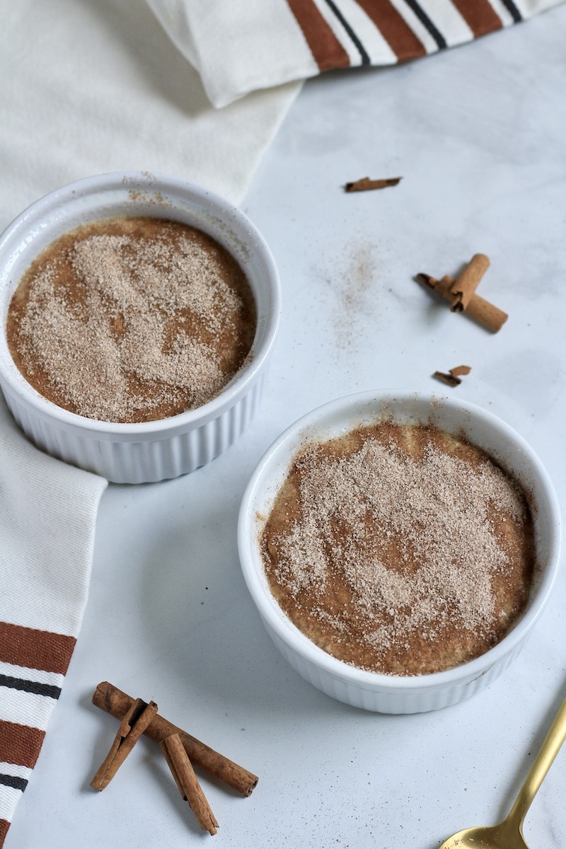 Top down photo of two ramekins of snickerdoodle baked oats topped with cinnamon sugar before baking.