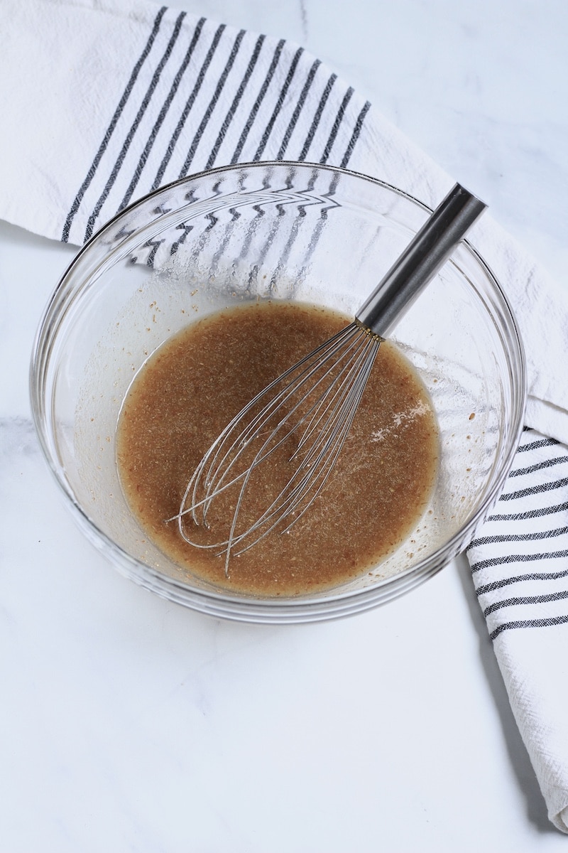 A glass bowl with a whisk and the liquid ingredients.