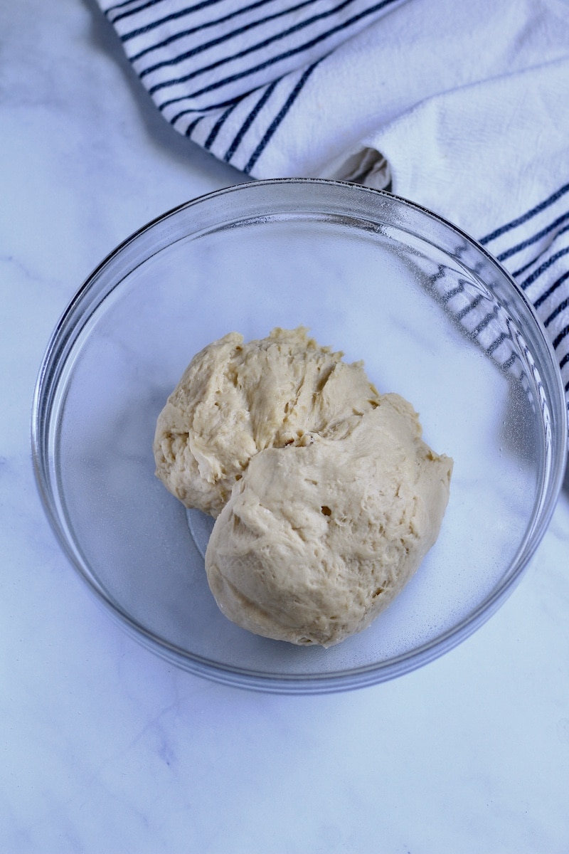 A glass bowl with dough before resting.